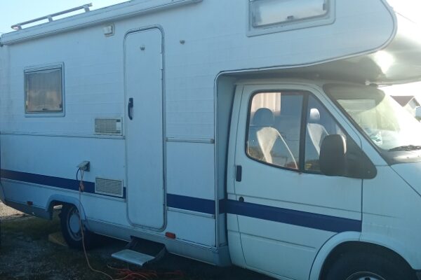 Camping-car blanc stationné avec câble électrique branché