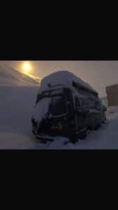 Camping-car enseveli sous la neige au coucher du soleil
