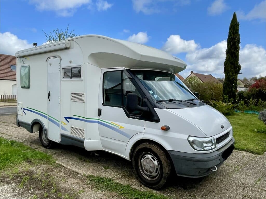 Camping-car blanc stationné devant une maison