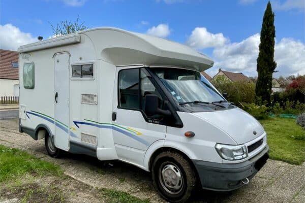 Camping-car blanc stationné devant une maison