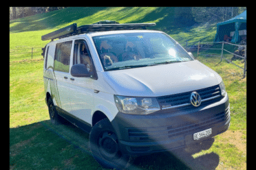 Van Volkswagen blanc garé dans un pré ensoleillé
