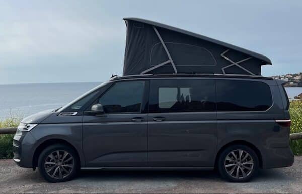 Van aménagé gris avec toit relevable face mer