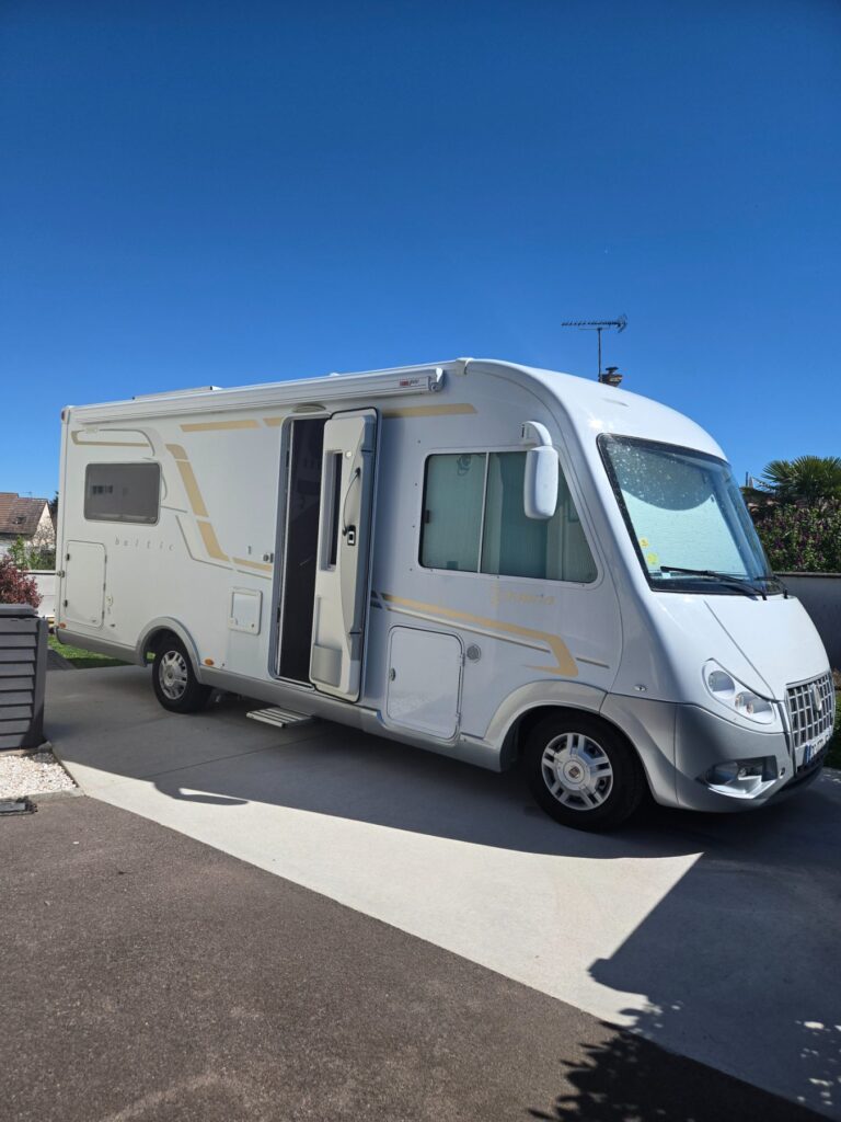 Camping-car blanc stationné dans une allée résidentielle
