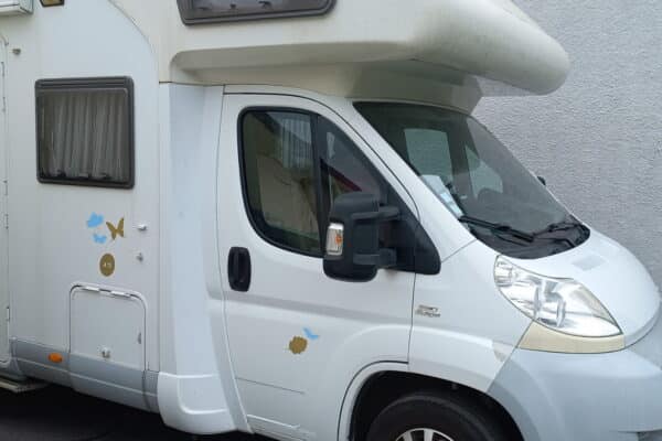 Camping-car blanc branché à une prise électrique