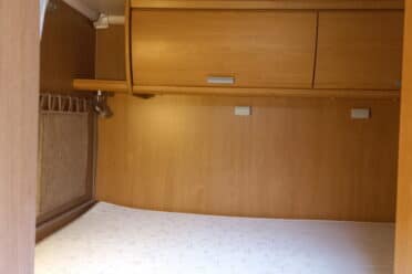 Interno della roulotte con letto in legno e spazio di stivaggio
