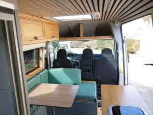 Intérieur de van aménagé avec coin repas en bois