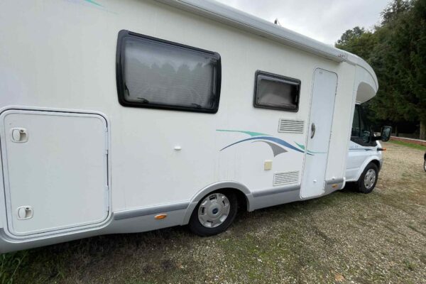 Camping-car blanc stationné sur terrain gravillonné