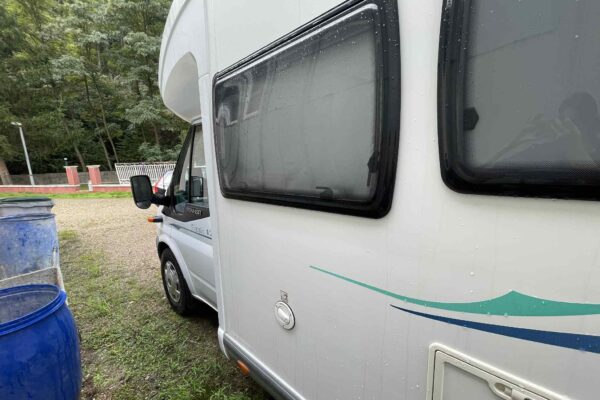 Camping-car blanc garé sous la pluie près d'arbres