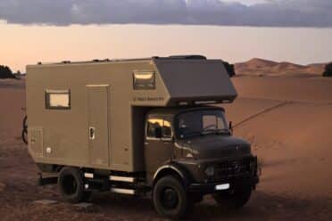 Camion aménagé stationné dans le désert au coucher du soleil