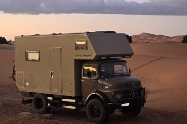 Camion aménagé stationné dans le désert au coucher du soleil
