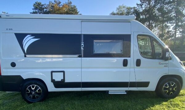 Fourgon aménagé blanc stationné sur pelouse