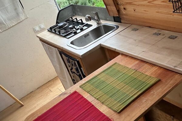 Petite kitchenette avec évier, gazinière et table en bois