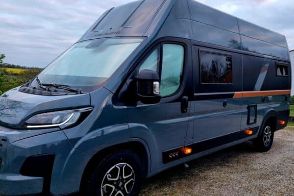 Fourgon aménagé gris stationné en extérieur nuageux