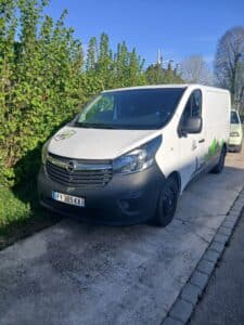 Camionnette blanche utilitaire garée près d’une haie