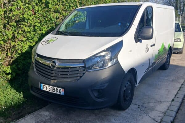 Camionnette blanche utilitaire garée près d’une haie