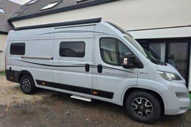 Furgone camperizzato bianco parcheggiato davanti a una casa moderna