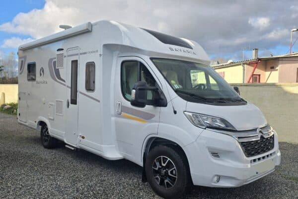 Camping-car Bavaria blanc stationné sur gravier