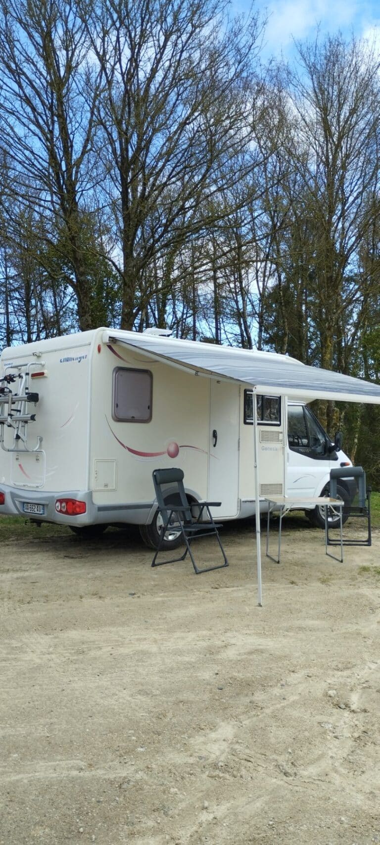 Camping-car avec auvent et chaises en forêt