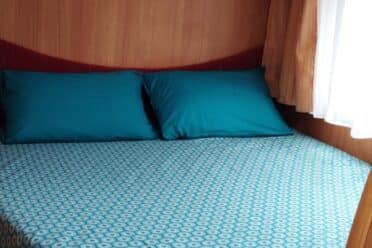 Lit double dans caravane avec rangements en bois
