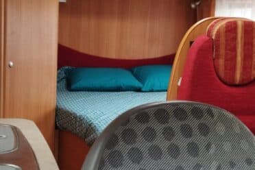 Interno del camper con letto e armadi in legno