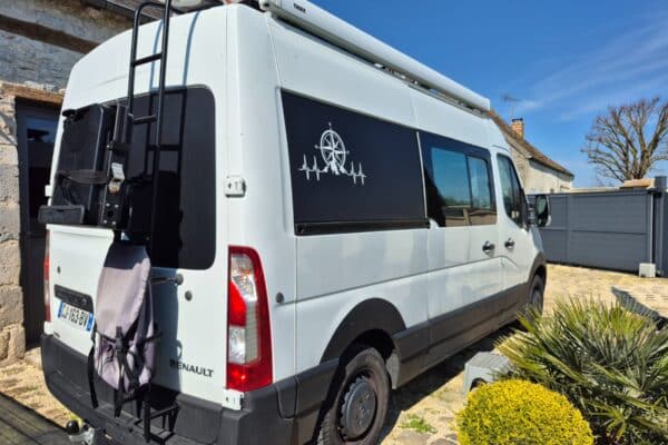 Fourgon aménagé Renault blanc garé devant maison