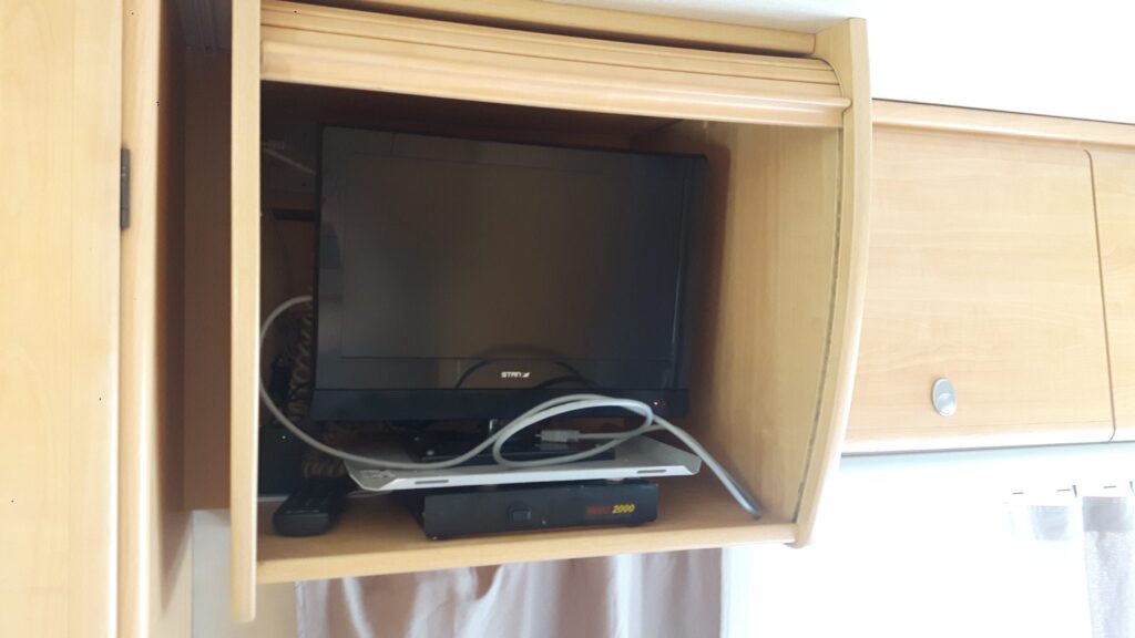 Téléviseur dans placard en bois avec câbles