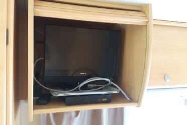 Téléviseur dans placard en bois avec câbles