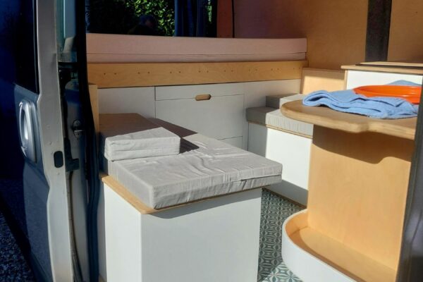 Intérieur aménagé d’un van avec banquettes et rangements