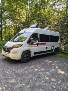 Fourgon aménagé blanc garé en forêt