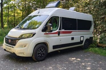 Furgone camperizzato bianco parcheggiato nella foresta