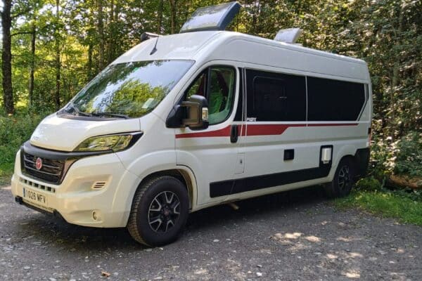 Fourgon aménagé blanc garé en forêt
