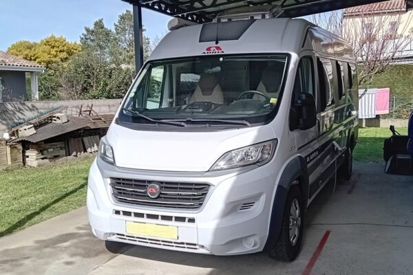 Camping-car blanc stationné sous un carport résidentiel