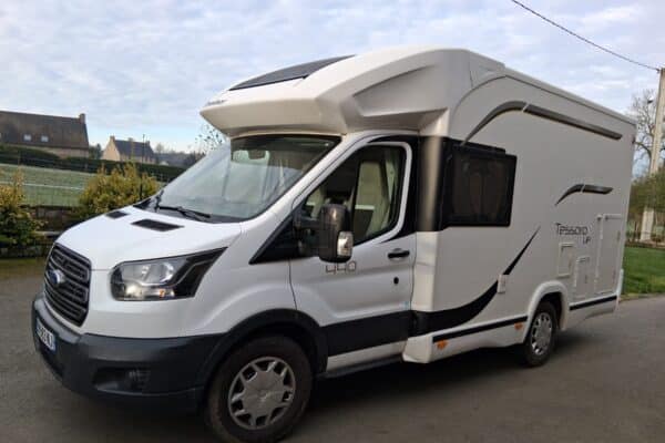Camping-car blanc stationné sur route rurale