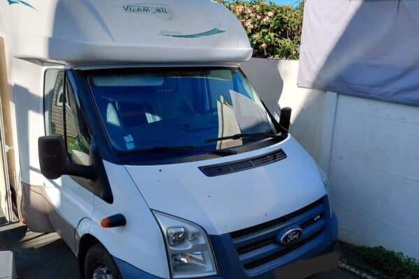 Camping-car blanc Ford garé près d’un mur