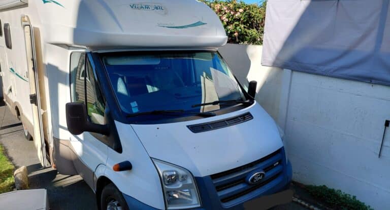 Camping-car blanc Ford garé près d’un mur