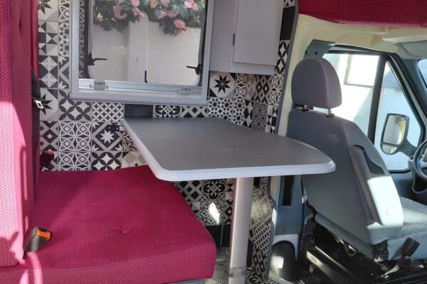 Coin repas de van aménagé avec banquette rouge