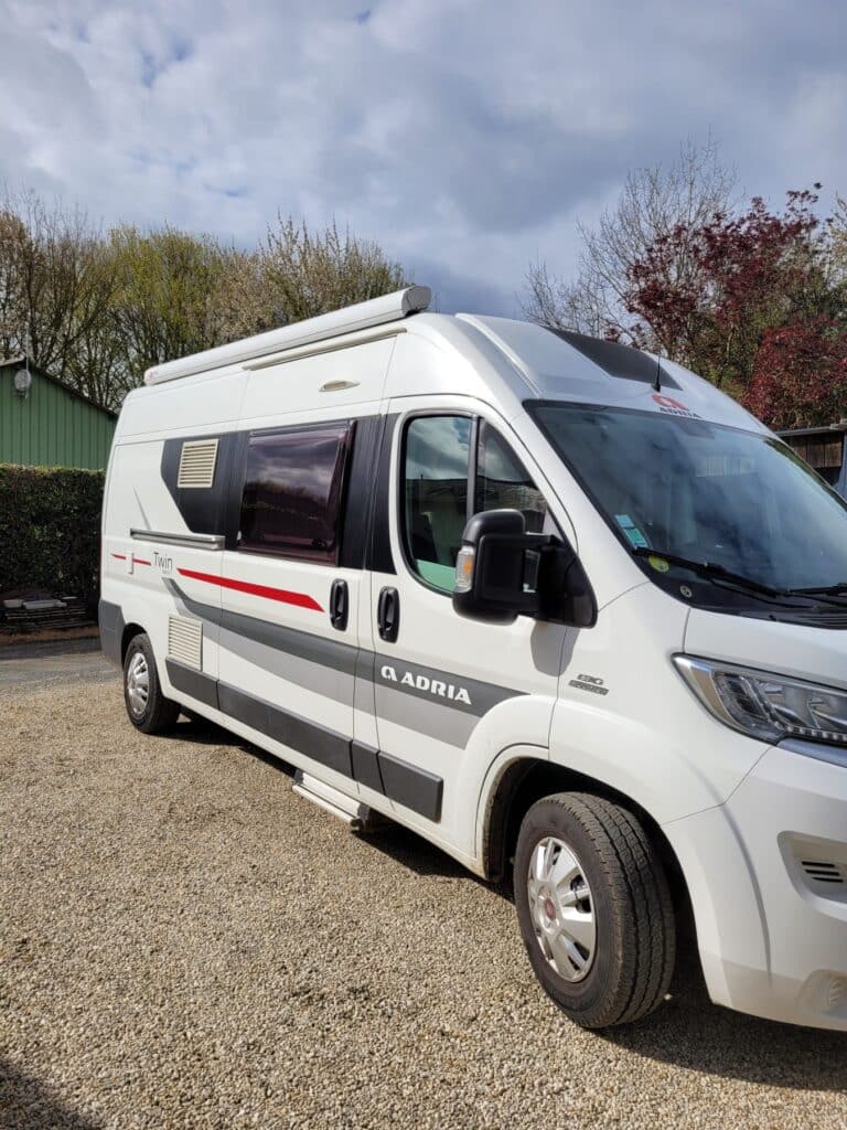 Camping-car Adria Twin blanc garé sur gravier