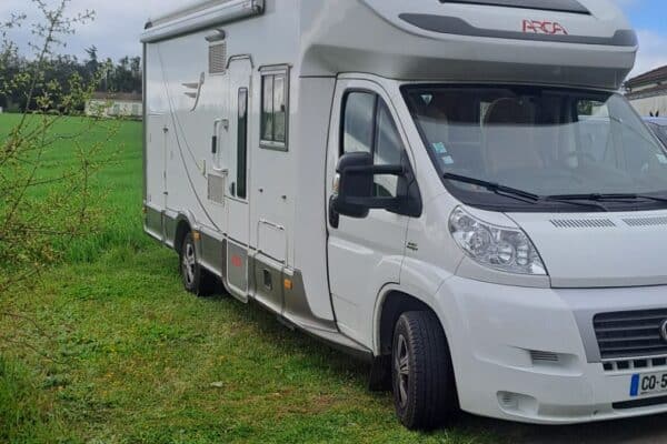 Camping-car blanc stationné en bord de champ