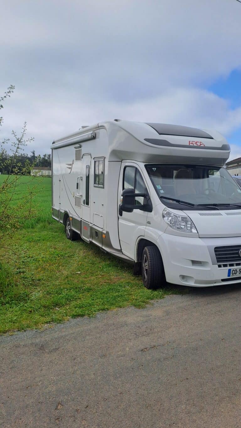 Camping-car blanc stationné en bord de champ