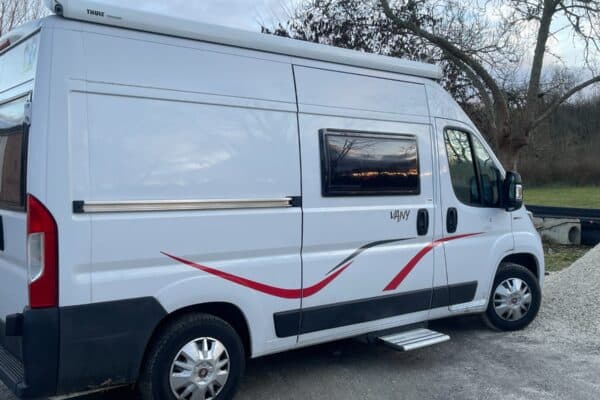 Fourgon aménagé blanc stationné en pleine nature