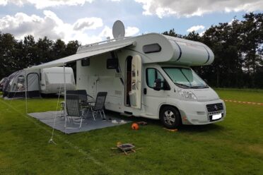 Camper con tenda installata su terreno erboso