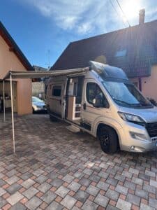 Camping-car blanc avec auvent déployé dans cour pavée