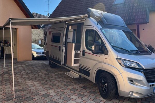 Camping-car blanc avec auvent déployé dans cour pavée