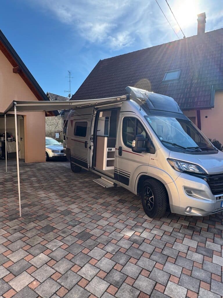 Camping-car blanc avec auvent déployé dans cour pavée