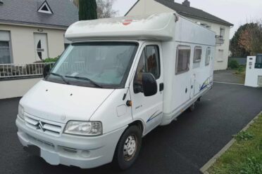 Camping-car blanc stationné dans rue résidentielle