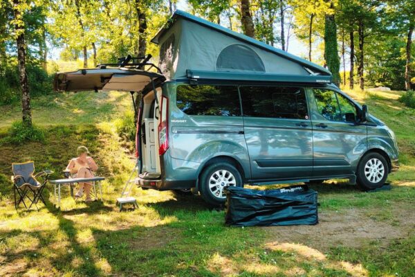 Van aménagé avec toit relevable en forêt