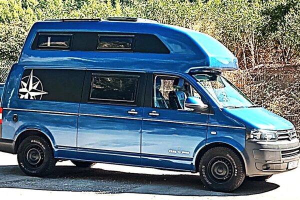 Van aménagé bleu avec toit relevable stationné en extérieur
