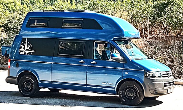 Van aménagé bleu avec toit relevable stationné en extérieur