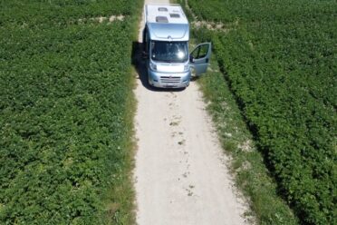Camping-car stationné sur chemin entre champs verdoyants