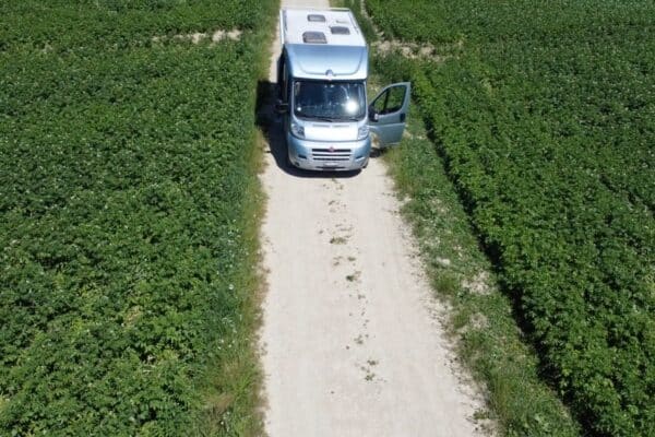 Camping-car stationné sur chemin entre champs verdoyants